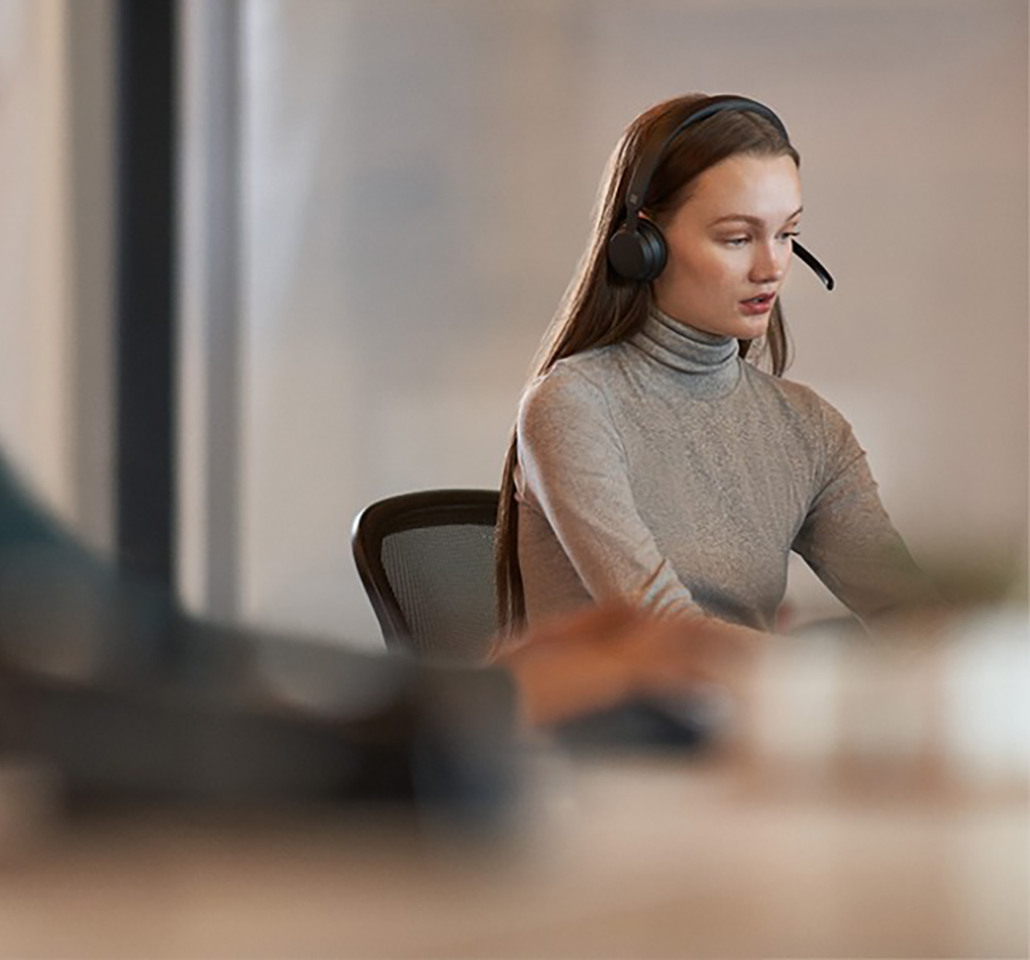 Woman wearing a headset and working at a laptop computer.