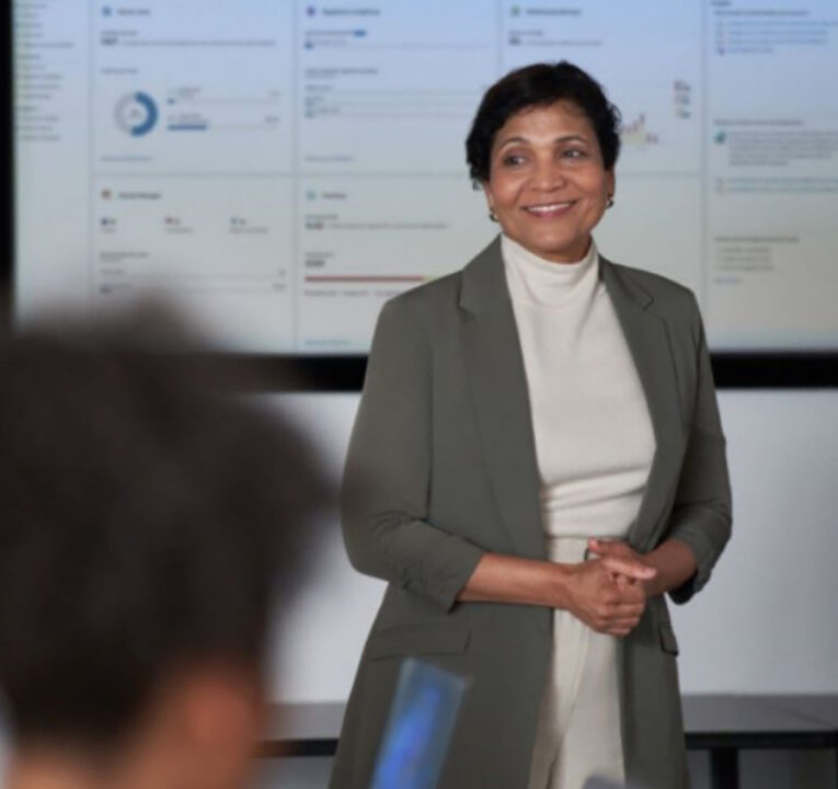 Woman giving a presentation to a room of people.